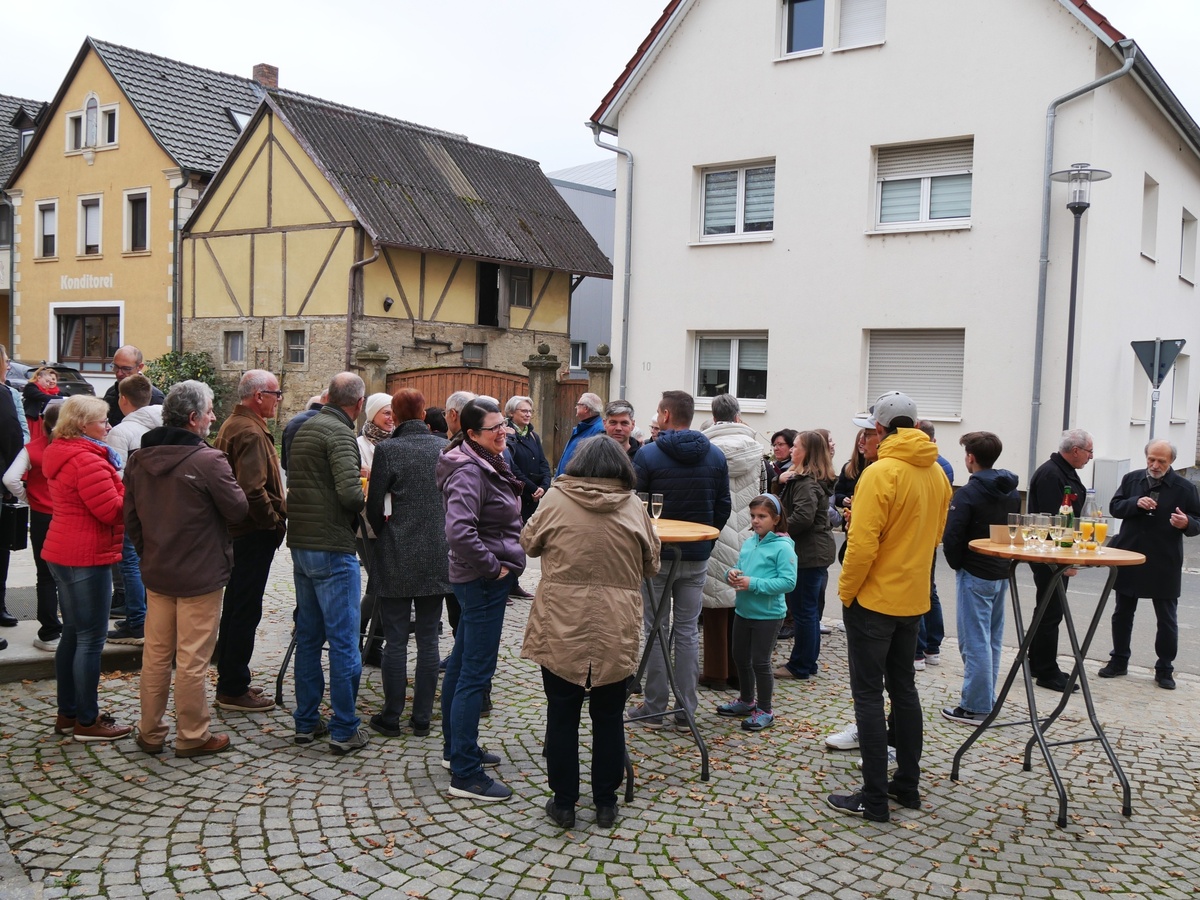 Auf dem Platz vor der Kirche stehen Menschen beieinander und unterhalten sich.